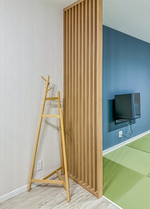 A room with a wooden ladder leaning against a wall, a television mounted on the wall, and a green area rug on the floor. - HANASTAY AYA (Osaka)