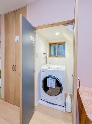 A laundry room with a washing machine, a drying machine, and a window above the machines. - HANASTAY AYA (Osaka)