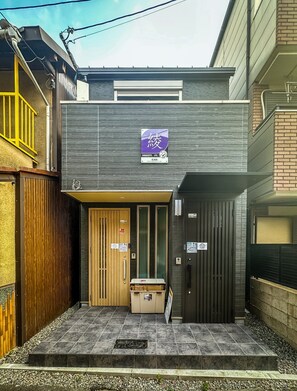 A modern building with a wooden door, a mailbox, and a sign with Japanese characters. - HANASTAY AYA (Osaka)