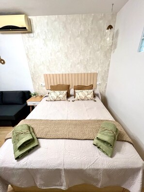 Une chambre d’hôtel comprenant un lit, une table de chevet, une tête de lit en bois et un appareil de climatisation fixé au mur.
