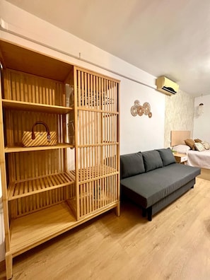 A room with a wooden wardrobe, a grey sofa, and a bed with a headboard. - Beautiful Apartment II: Free Welcome Package (Torremolinos)