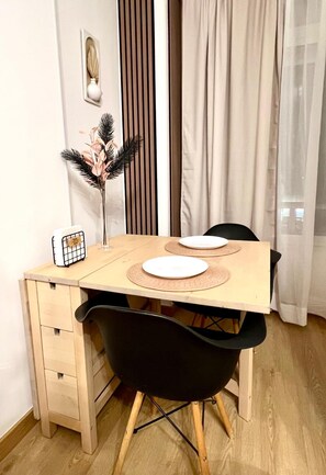 A dining area with a wooden table, two black chairs, and a vase with pink flowers. - Beautiful Apartment II: Free Welcome Package (Torremolinos)