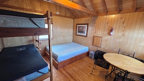 A cabin with bunk beds, a small table, and a chair. - Bear Necessities Camping Cabin 3 (West Yellowstone)