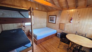 A cabin with bunk beds, a small table, and a chair. - Bear Necessities Camping Cabin 4 (West Yellowstone)