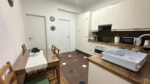 Una cocina compacta con gabinetes blancos, un microondas, un tostador y un lavamanos.