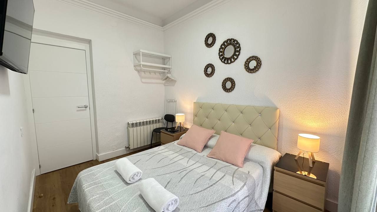 Een keurig opgemaakt slaapkamer met een bed, nachtkastjes, een kledingkast en decoratieve wandversiering.