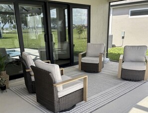 Un espace patio aménagé avec des meubles en osier et offrant une vue sur une pelouse.