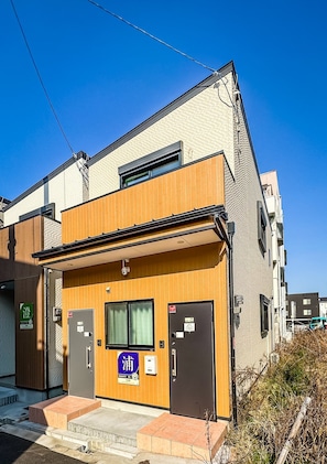 A modern building with a wooden facade, two doors, and a window. - HANASTAY URA (Osaka)