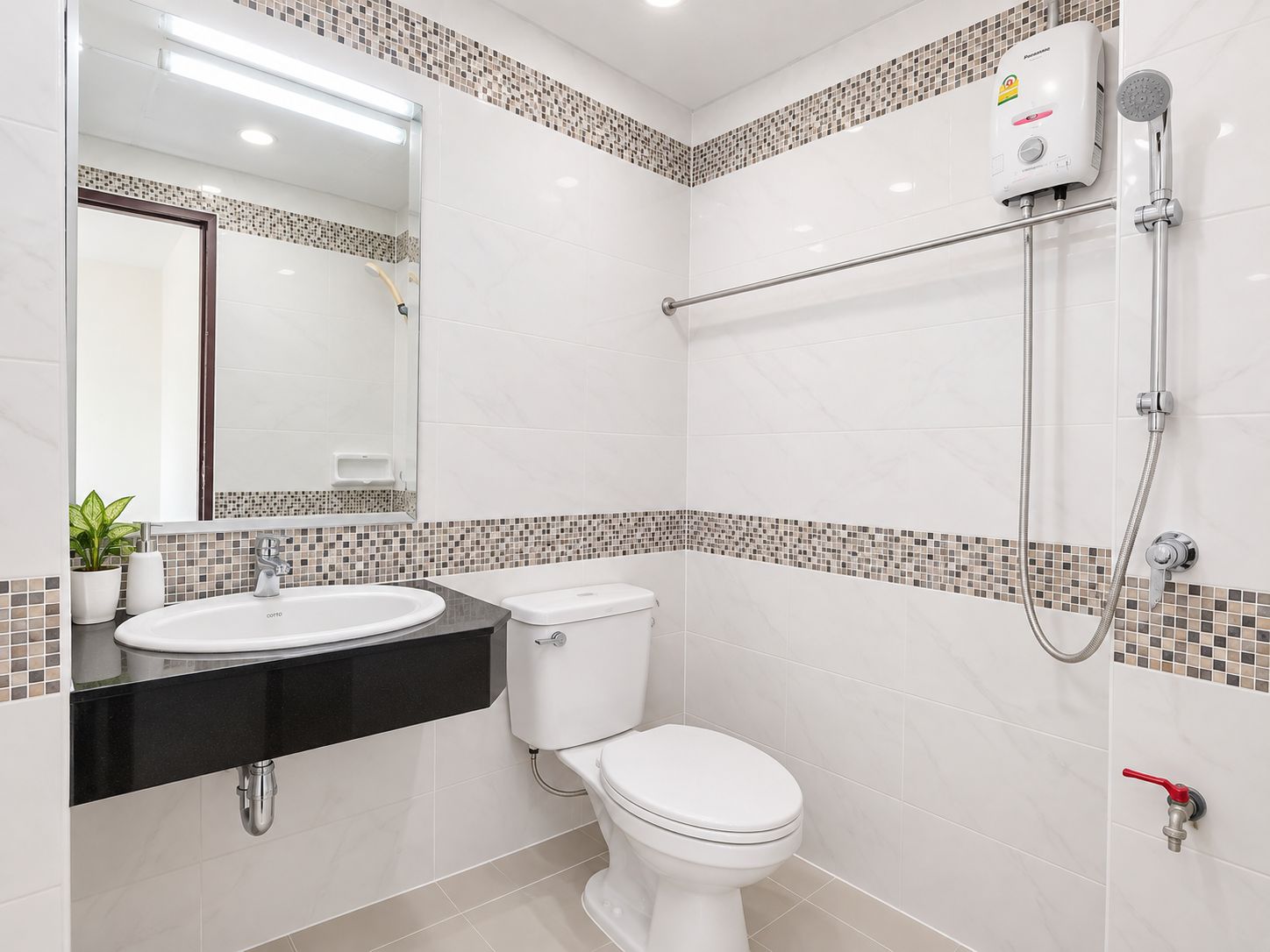A bathroom with a white toilet, a sink, a shower, and a mirror.