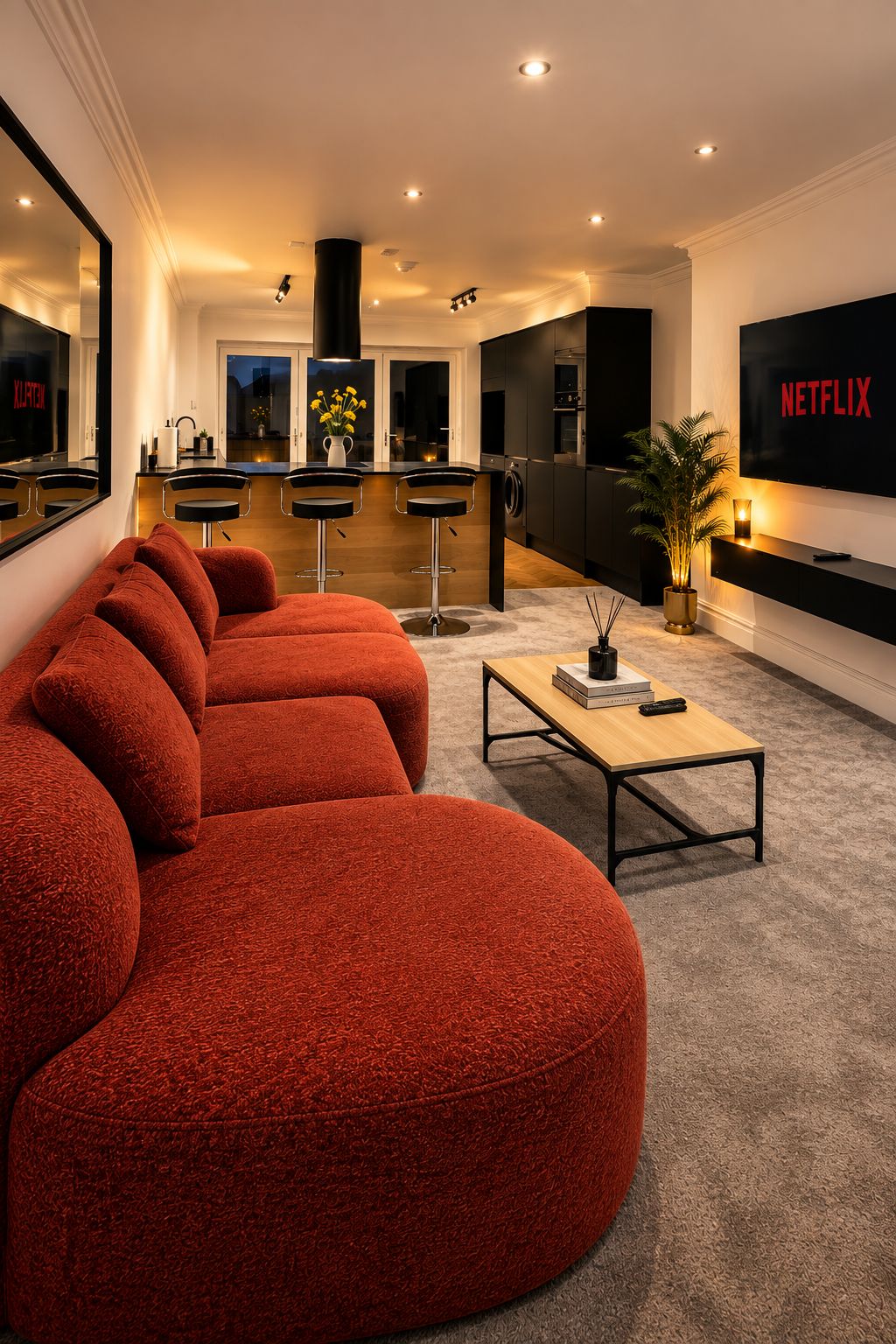 Un salon moderne avec un grand canapé rouge, une table basse et un téléviseur à écran plat affichant le logo « NETFLIX ».