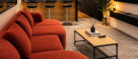 A modern living room with a large red sofa, a coffee table, and a flat-screen TV displaying 'NETFLIX'.