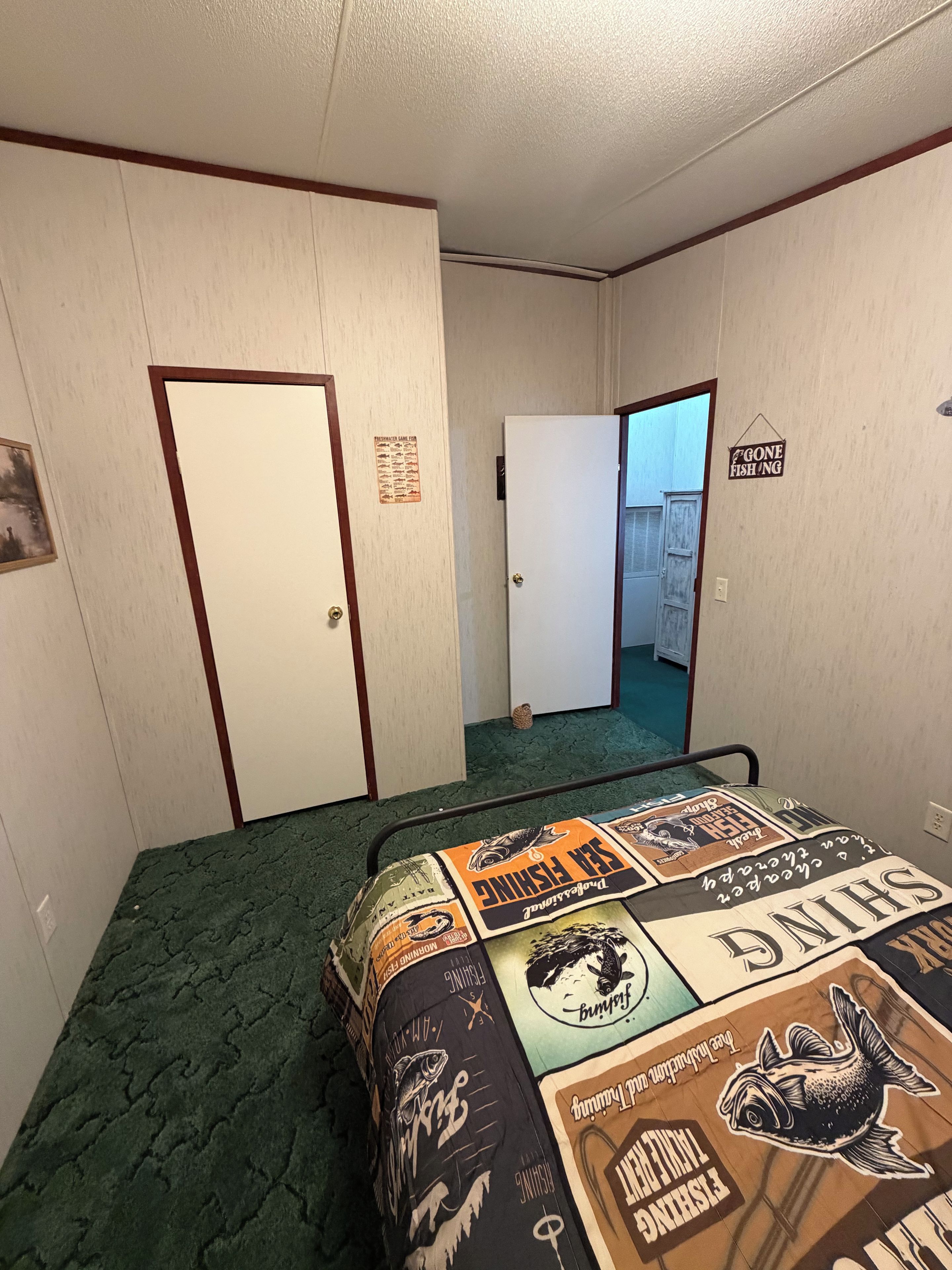 Quarto de hotel com cama, porta, placa na parede e corredor.