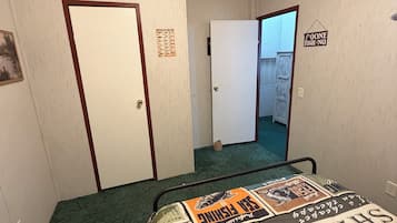 Quarto de hotel com cama, porta, placa na parede e corredor.