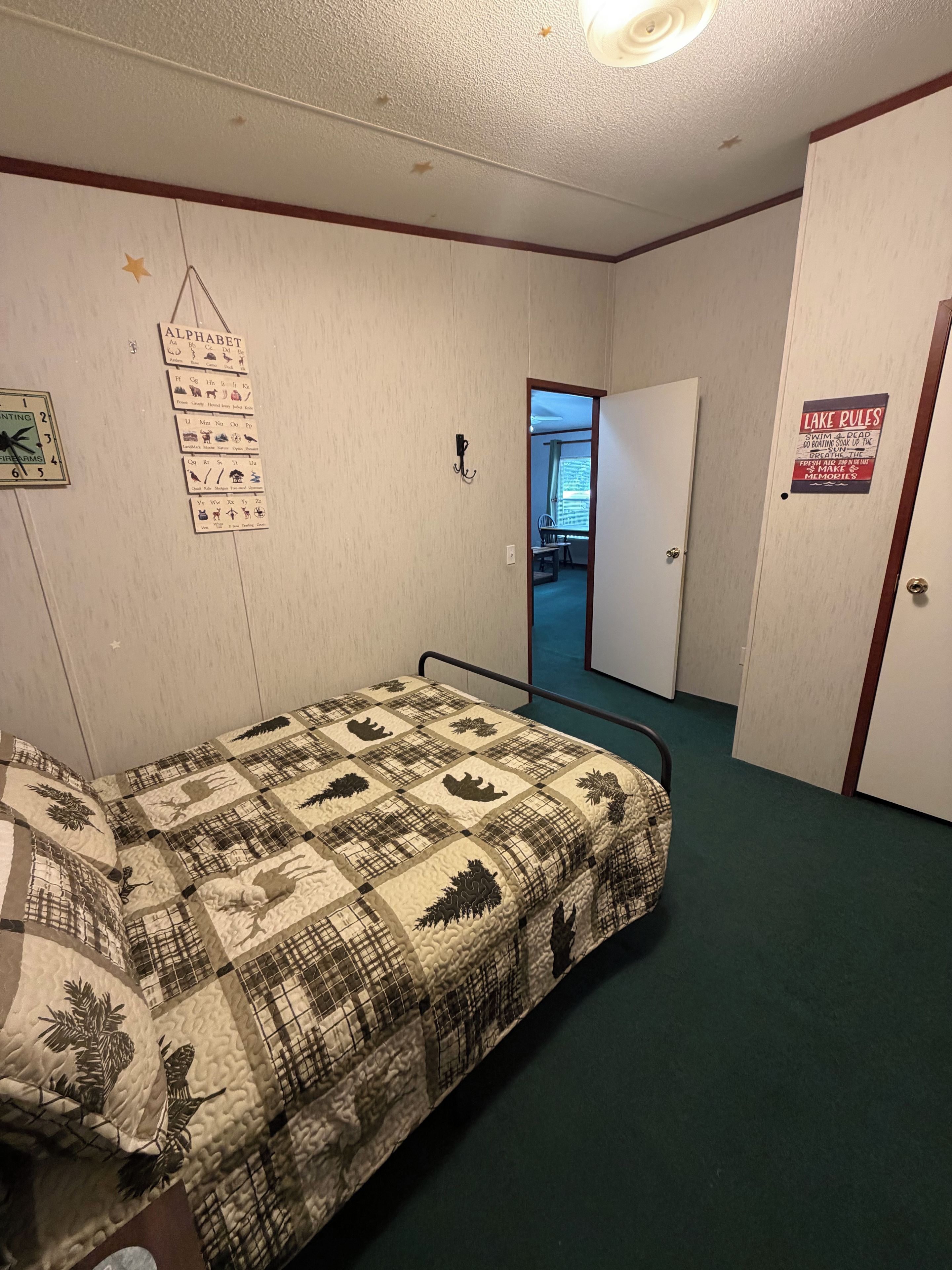 Ein Zimmer mit einem Bett, einer Wanduhr, einer Tür und einem Schild an der Wand.