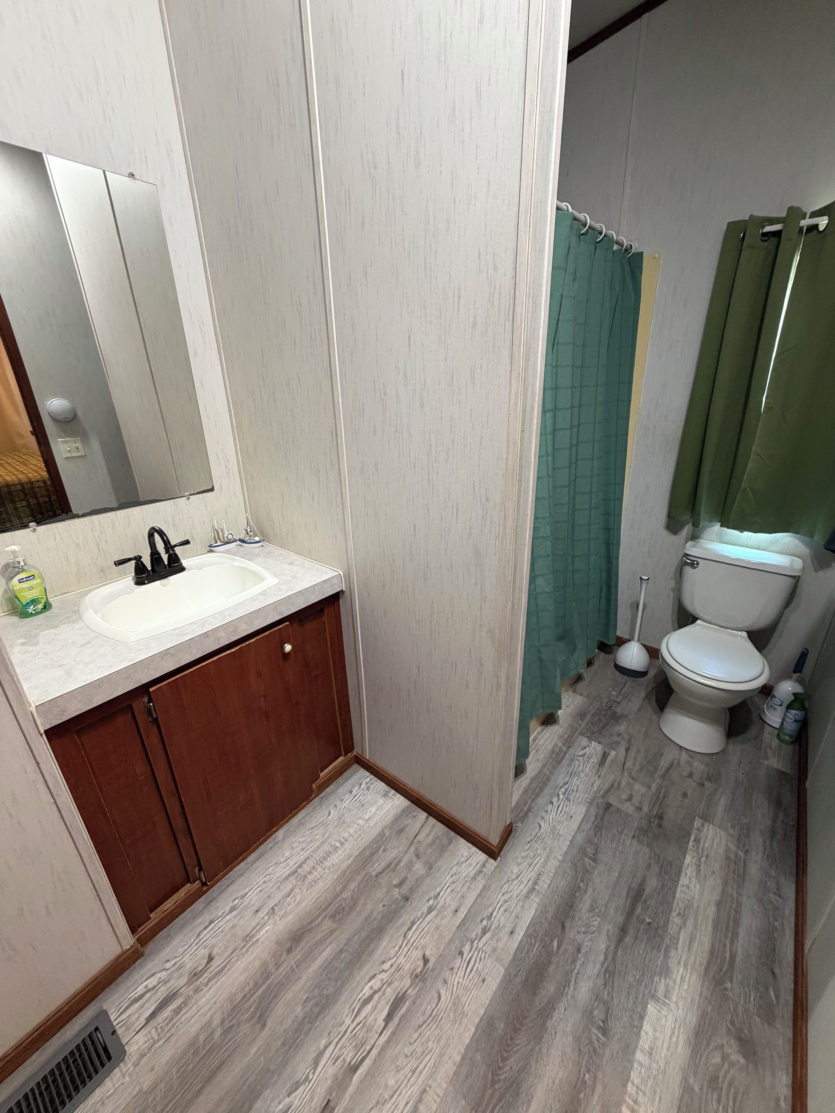 A bathroom with a sink, mirror, toilet, and shower curtain.