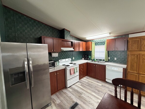 A compact kitchen with a refrigerator, stove, microwave, and sink.