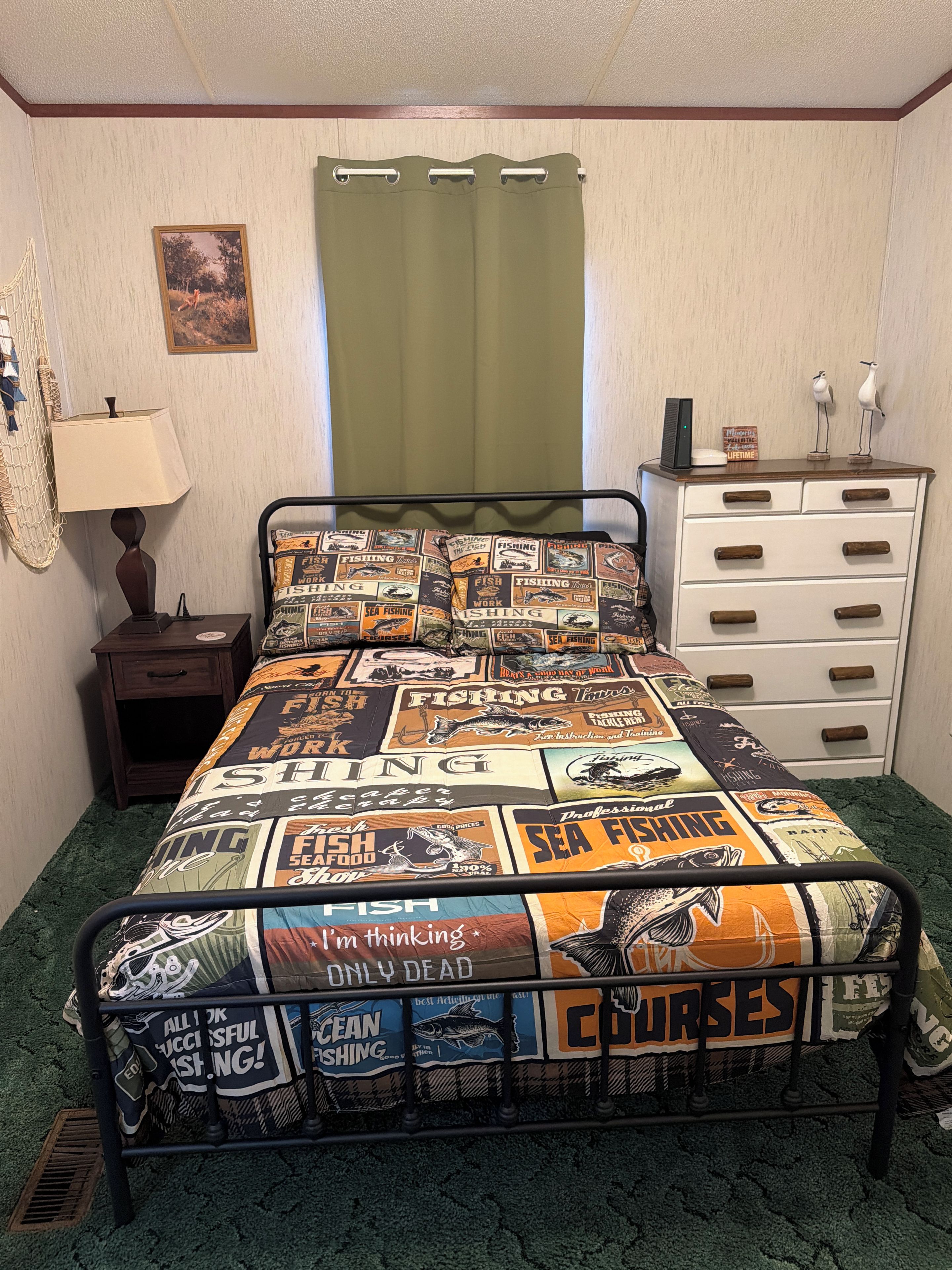 Quarto com cama, penteadeira, mesa de cabeceira, abajur, quadro na parede e cortina.