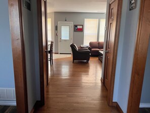 Un pasillo con piso de madera que conduce a una sala de estar con un sofá y una silla.