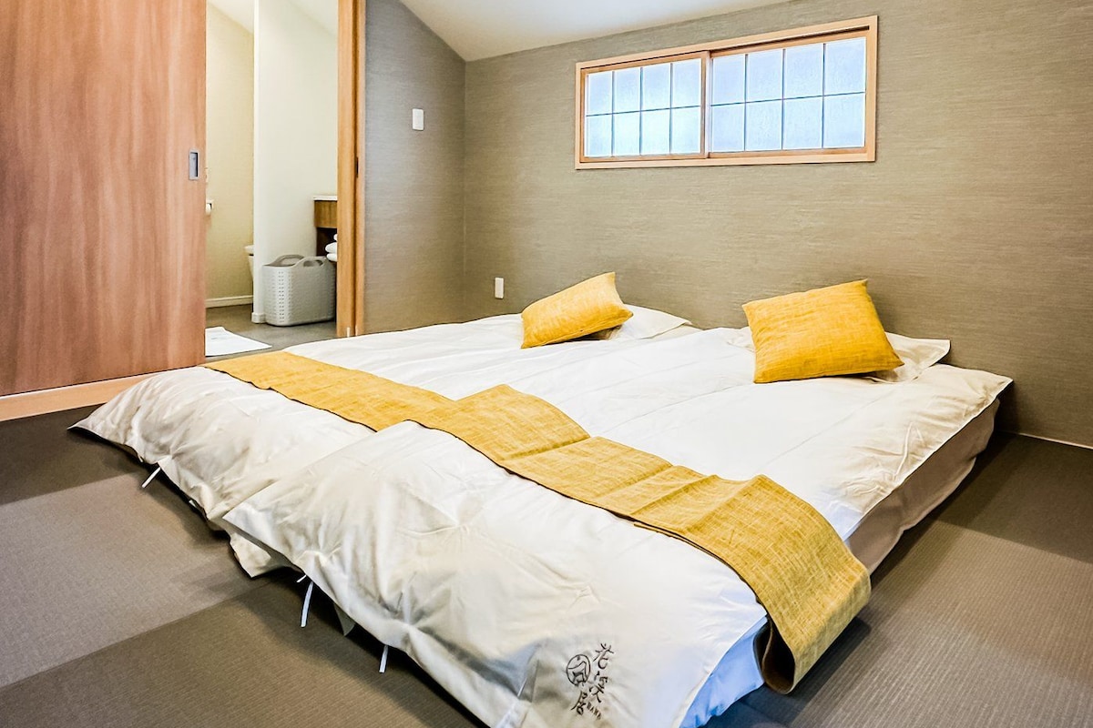 A modern bedroom with a large bed, a wooden wardrobe, and a window with a view.