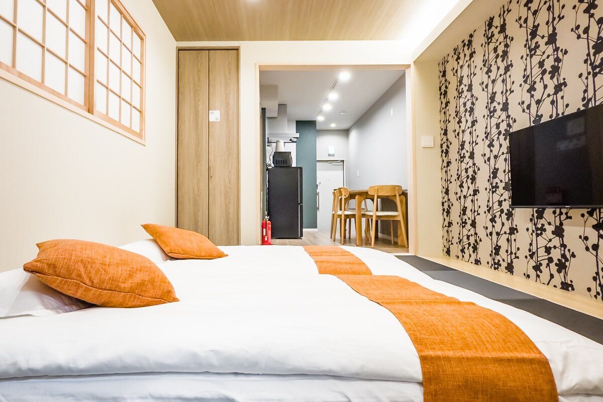 A hotel room with a large bed, a TV, a desk, and a chair.