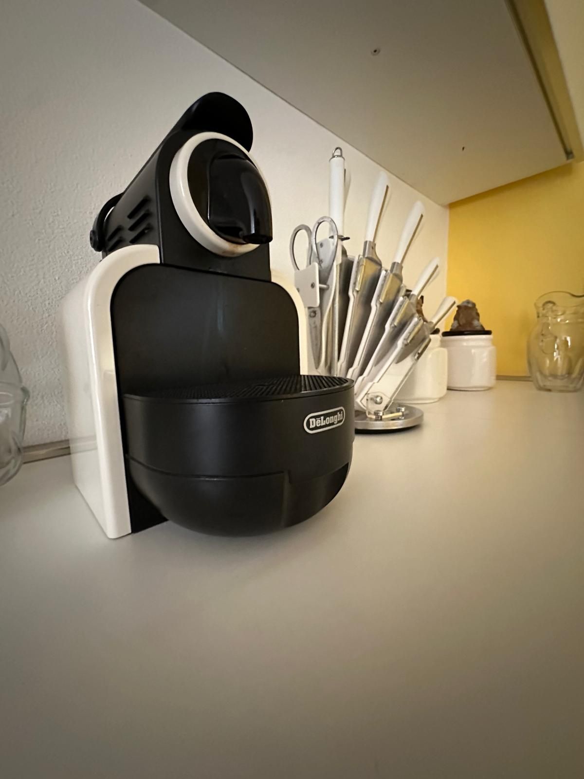 Eine Küchenarbeitsplatte mit einem schwarz-weißen Gerät, einem Messerset und einem kleinen weißen Behälter.