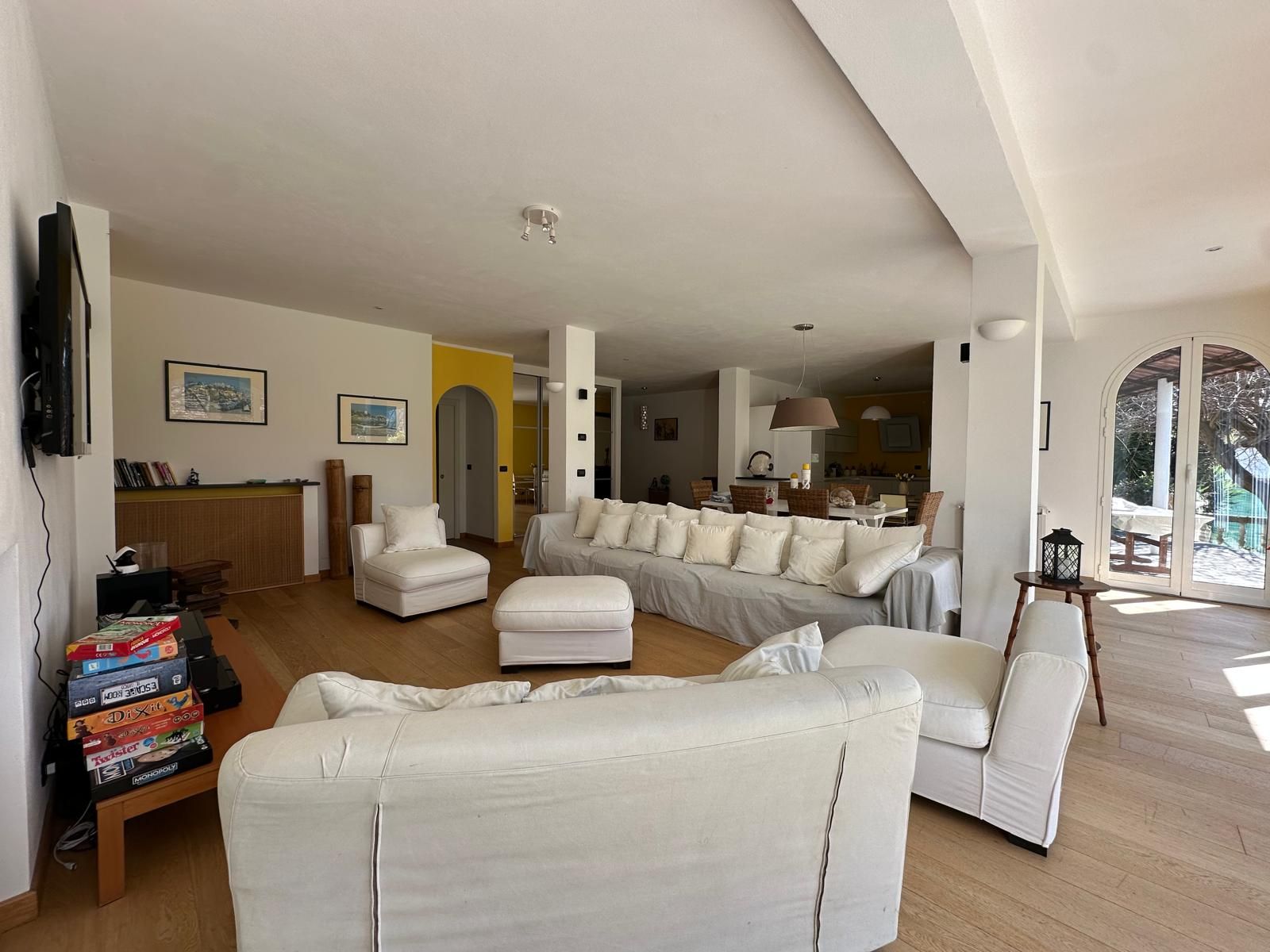 A spacious living room with a large sofa, a coffee table, and a television mounted on the wall.