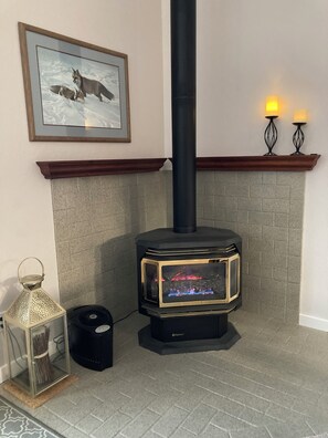 A wood-burning stove with a glass front, a framed picture above it, and a mantel with two candle holders. - NEW LISTING! Lakefront Home for Rest and Recreation (Pagosa Springs)