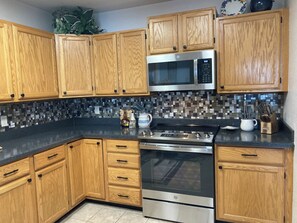 A kitchen with wooden cabinets, a stainless steel microwave, and a stove. - NEW LISTING! Lakefront Home for Rest and Recreation (Pagosa Springs)