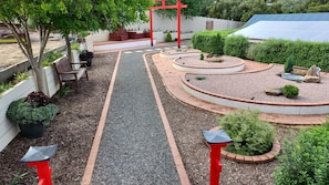A landscaped garden with a gravel path, red benches, and a red structure. - New one of two 2-bedroom units in Gawler-Barossa. Unique garden. Close to shops (Evanston)