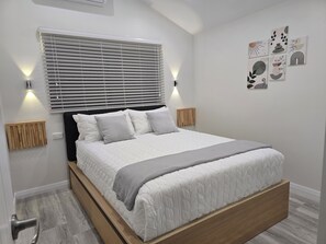 A modern bedroom with a bed, bedside lamps, a radiator, and wall art. - New one of two 2-bedroom units in Gawler-Barossa. Unique garden. Close to shops (Evanston)