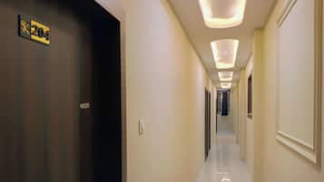 Un corridoio d'hotel con una porta scura contrassegnata dal numero '204', un pavimento piastrellato e illuminazione a incasso.