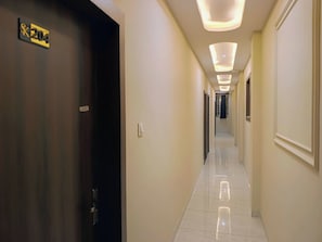 A hotel corridor with a dark door marked '204', a tiled floor, and recessed lighting. - Hotel Sai Kripa (Ujjain)
