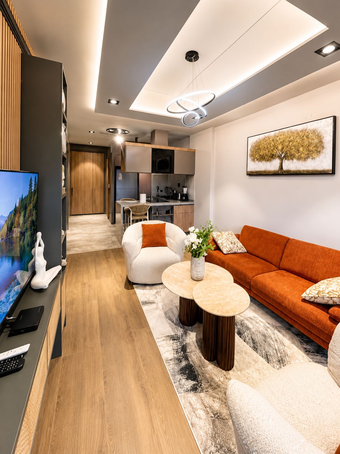Een moderne woonkamer met een bank, fauteuils, een salontafel en een televisie.