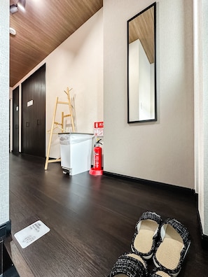 Un pasillo de hotel con piso de madera, un extintor, una escalera y un espejo en la pared.