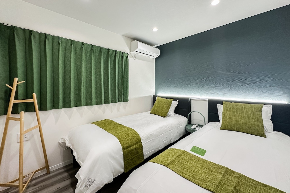 A hotel room with two beds, a ladder, an air conditioning unit, and a wall-mounted light fixture.