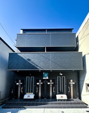 A modern building with a flat roof and a sign indicating a parking area. - HANASTAY KAERU (Osaka)