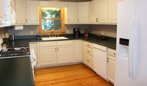 A kitchen with white cabinets, a black countertop, a stainless steel sink, and a built-in dishwasher. - 3-bedroom cabin in beautiful Ellijay with cool mountain vibes (Ellijay)