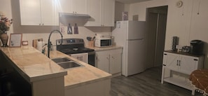 A kitchen with white cabinets, a stove, a microwave, and a refrigerator. - The Colorado Cowboy Hideaway - a 3 bed, 2 bath gem located in Bullhead City! (Bullhead City)