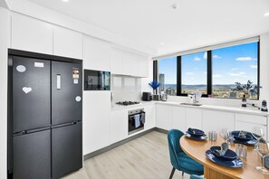 A modern kitchen with a built-in oven, a refrigerator, and a window with a city view. - 3 Bedroom Broadwater & Mountain Views (Surfers Paradise)