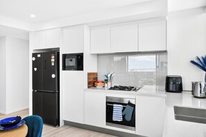 A modern kitchen with a black refrigerator, a microwave, a stove, and an oven. - 3 Bedroom Broadwater & Mountain Views (Surfers Paradise)