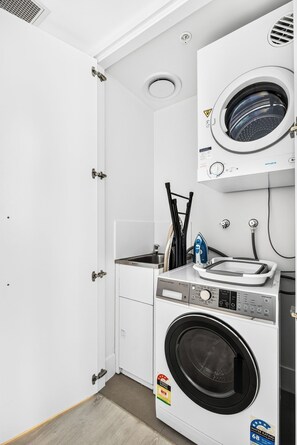 A compact laundry room with a front-loading washer and dryer, a small sink, and a towel rack. - 3 Bedroom Broadwater & Mountain Views (Surfers Paradise)