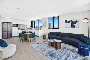 A modern living room with a dark grey sofa, blue chairs, and a round coffee table. - 3 Bedroom Broadwater & Mountain Views (Surfers Paradise)