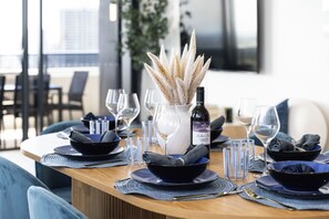 A dining table set with blue plates, clear glasses, and a bottle of wine. - 3 Bedroom Broadwater & Mountain Views (Surfers Paradise)