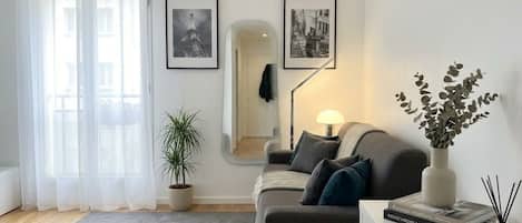 A modern living room with a sofa, a coffee table, a potted plant, and framed pictures on the wall.