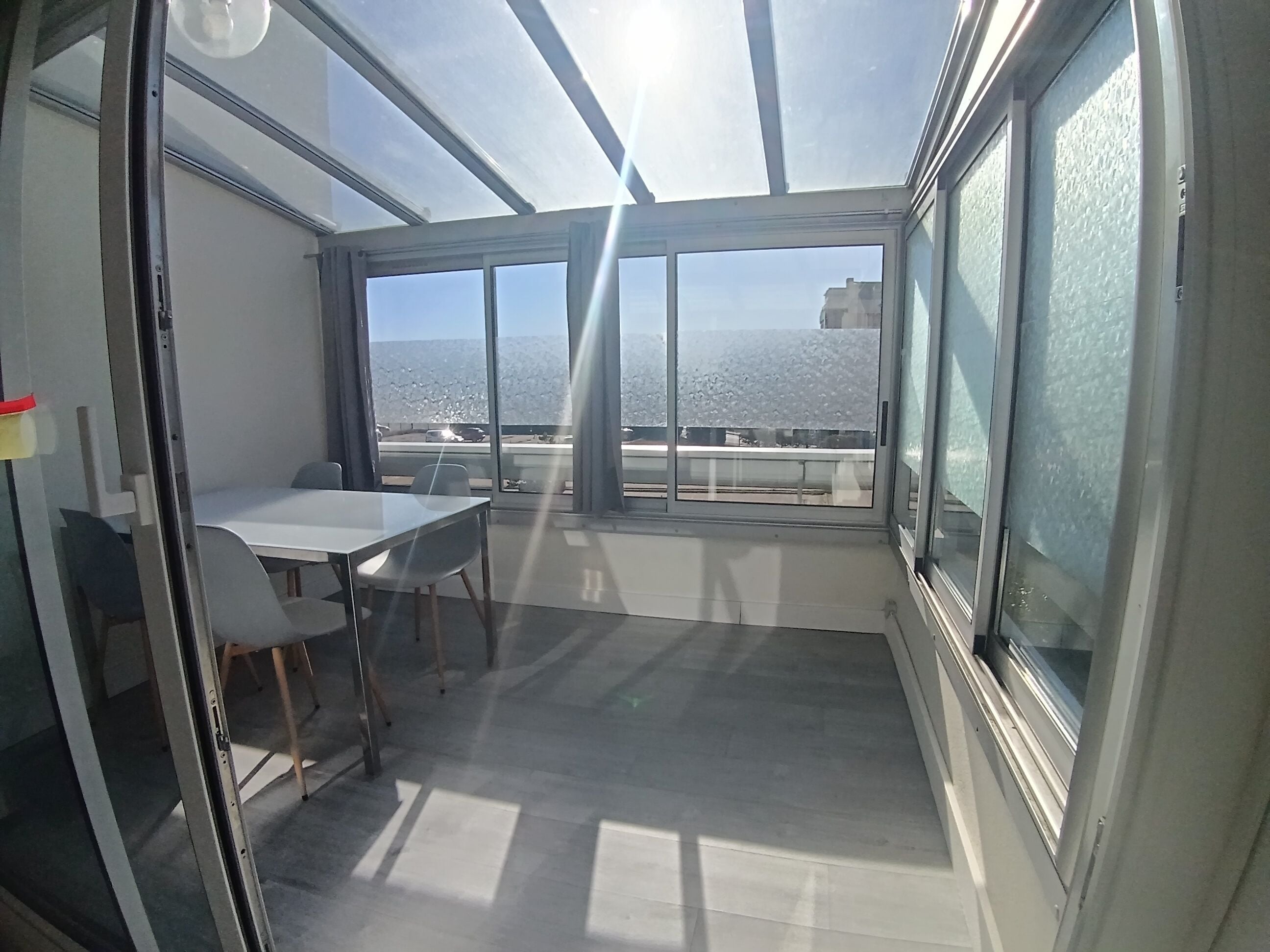 Une pièce avec une table et des chaises, de grandes fenêtres et une vue sur la mer.