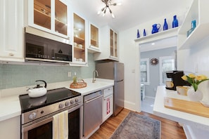 A modern kitchen with white cabinetry, a stainless steel stove, and a microwave. - Charming Updated Historic Home, Walk to Downtown, Shops, and Restaurants, $300 in Free Tickets! (St. Augustine)
