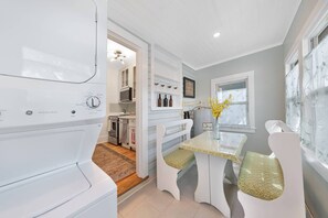 A kitchen with white cabinetry, a dining table with patterned chairs, and a view of the adjacent living area. - Charming Updated Historic Home, Walk to Downtown, Shops, and Restaurants, $300 in Free Tickets! (St. Augustine)