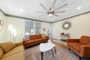 A living room with a ceiling fan, a sofa, a coffee table, and a rug. - Walk to Downtown, Shops, Restaurants! Charming Historic Home, Screened Porch, $300 in Free Tickets! (St. Augustine)