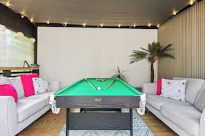 A pool table in a room with a sofa and a plant. - Wigan Bungalow near Hospital, Stadium own Parking (Wigan)