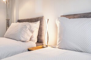 A neatly made bed with a wooden headboard, a bedside lamp, and a pillow with a dotted pattern. - Wigan Bungalow near Hospital, Stadium own Parking (Wigan)